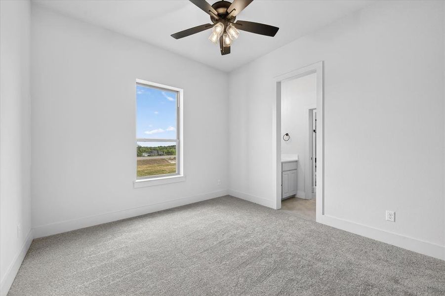 Unfurnished bedroom featuring light colored carpet, a ceiling fan, and ensuite bathroom