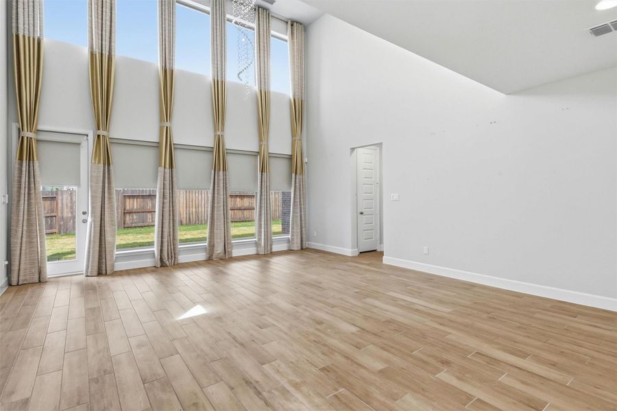 Floor-to-ceiling windows frame the backyard while filling the family room with sunlight throughout the day. The impressive ceiling height and open design create an airy, welcoming atmosphere that truly serves as the centerpiece of the home.