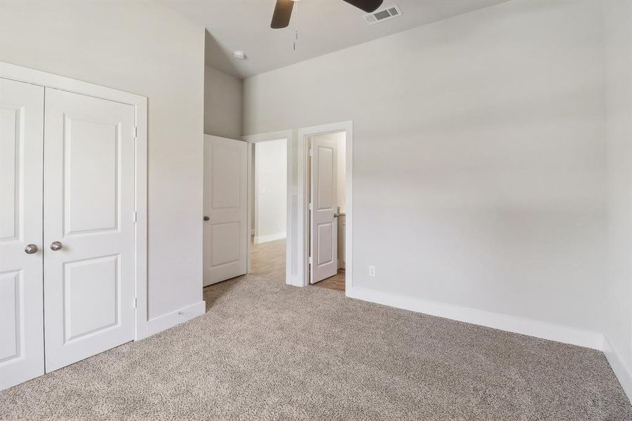 Unfurnished bedroom featuring a closet, light colored carpet, and ceiling fan