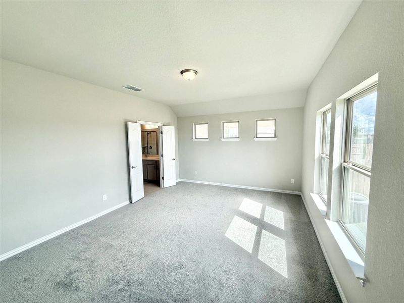 Unfurnished bedroom featuring multiple windows, light carpet, and connected bathroom Unfurnished bedroom featuring multiple windows, light carpet, and connected bathroom