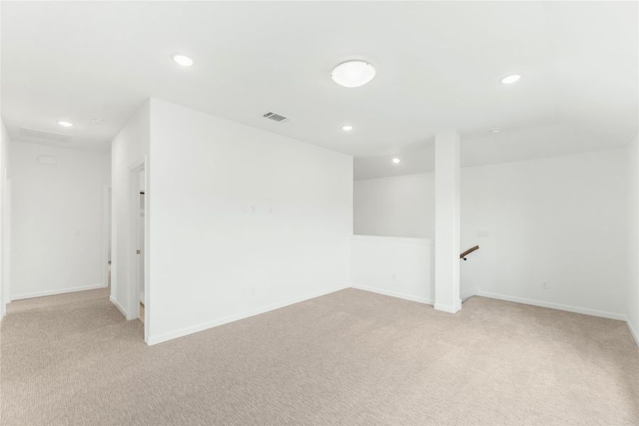 Open bonus room with beige carpet, white walls, recessed lighting, and staircase opening