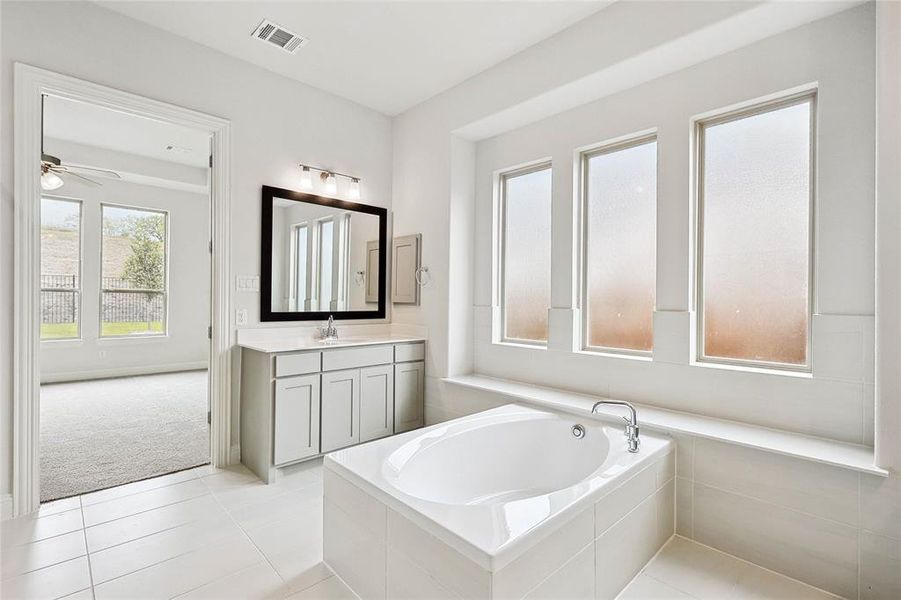 Bathroom with vanity, tiled tub, tile patterned flooring, and ceiling fan