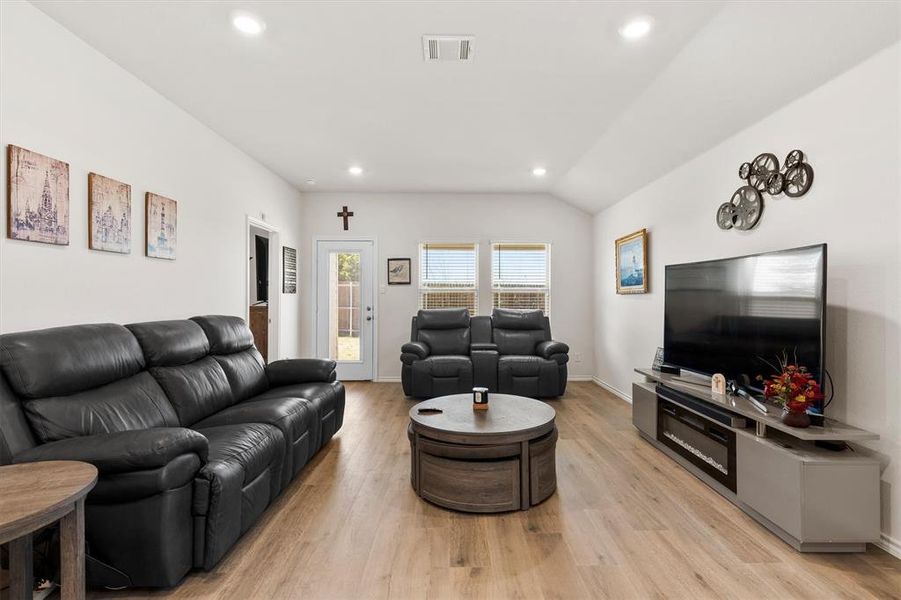 Living room with lofted ceiling, light wood finished floors, and recessed lighting Living room with lofted ceiling, light wood finished floors, and recessed lighting
