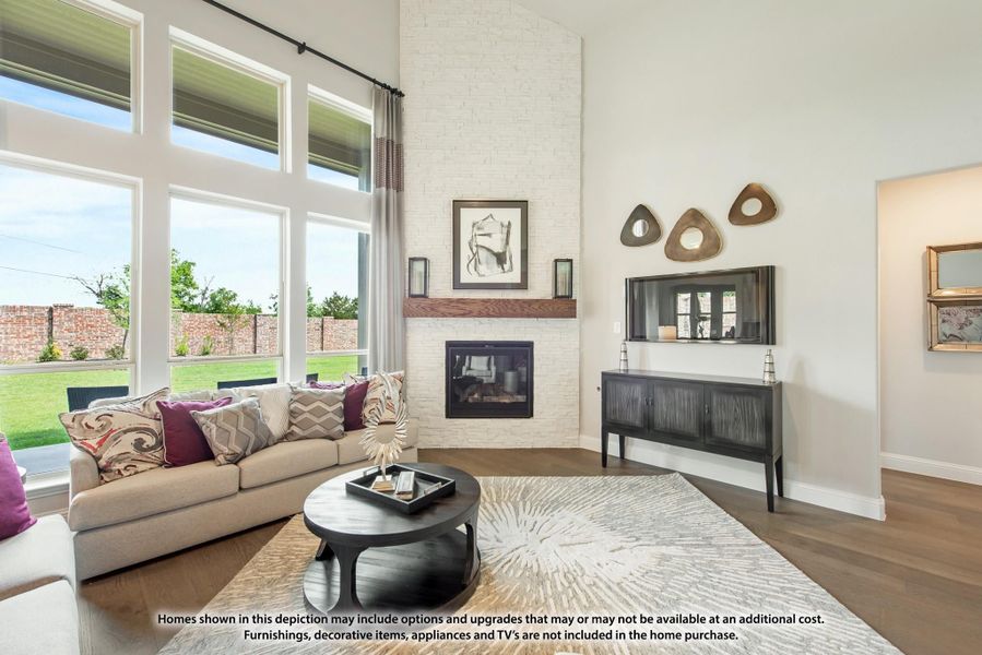 Living room with two-story white brick fireplace, large windows, hardwood floors, and neutral sofa with colorful pillows