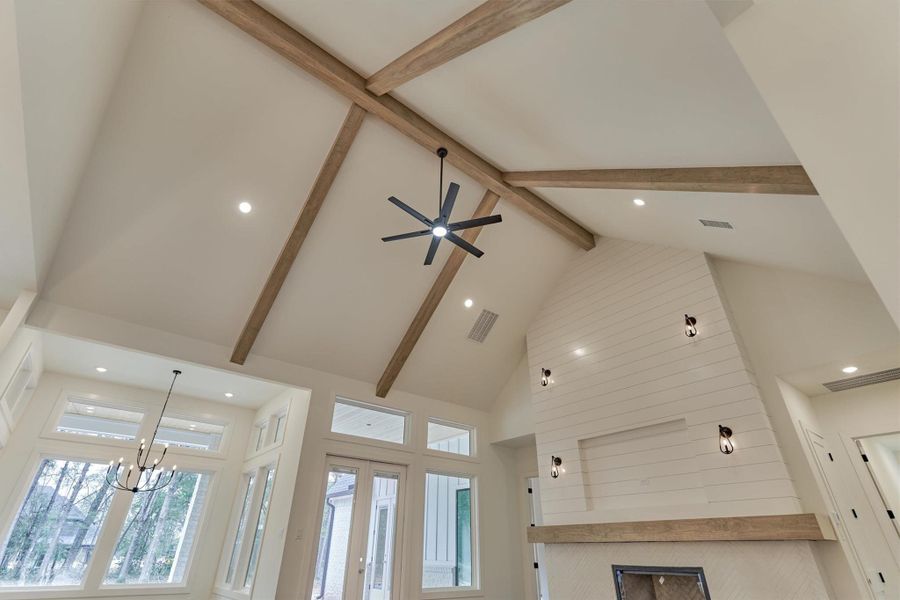 Vaulted living room ceiling with exposed wood beams, modern lighting, and a striking shiplap fireplace wall creating an elevated, designer look