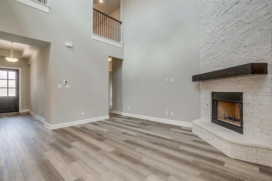 Unfurnished living room featuring a fireplace, hardwood / wood-style floors, and a high ceiling