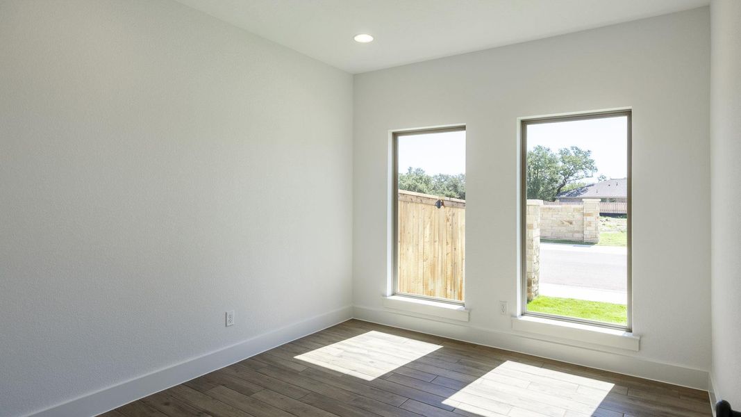 Empty room with dark wood-type flooring and recessed lighting