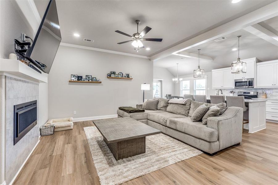 Living area featuring light wood-style floors, a chandelier, ceiling fan, a tile fireplace, and recessed lighting Living area featuring light wood-style floors, a chandelier, ceiling fan, a tile fireplace, and recessed lighting