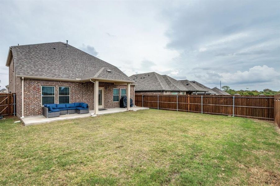 Rear view of property featuring a patio, a fenced backyard, brick siding, roof with shingles, and outdoor lounge area