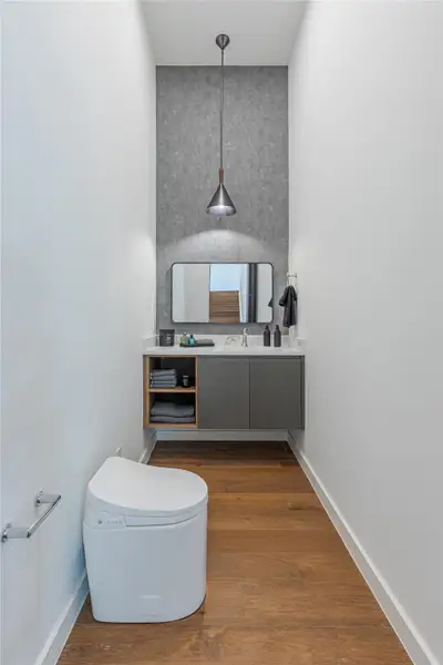 A well-appointed lavatory boasts warm hardwood flooring and modern vanity with sleek fixtures.