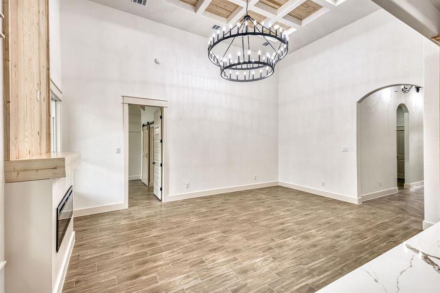 Unfurnished dining area with arched walkways, wood tiled floors, coffered ceiling, and a chandelier