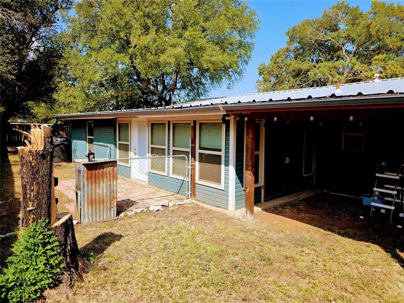 Rear view of property featuring a metal roof and a lawn Rear view of property featuring a metal roof and a lawn