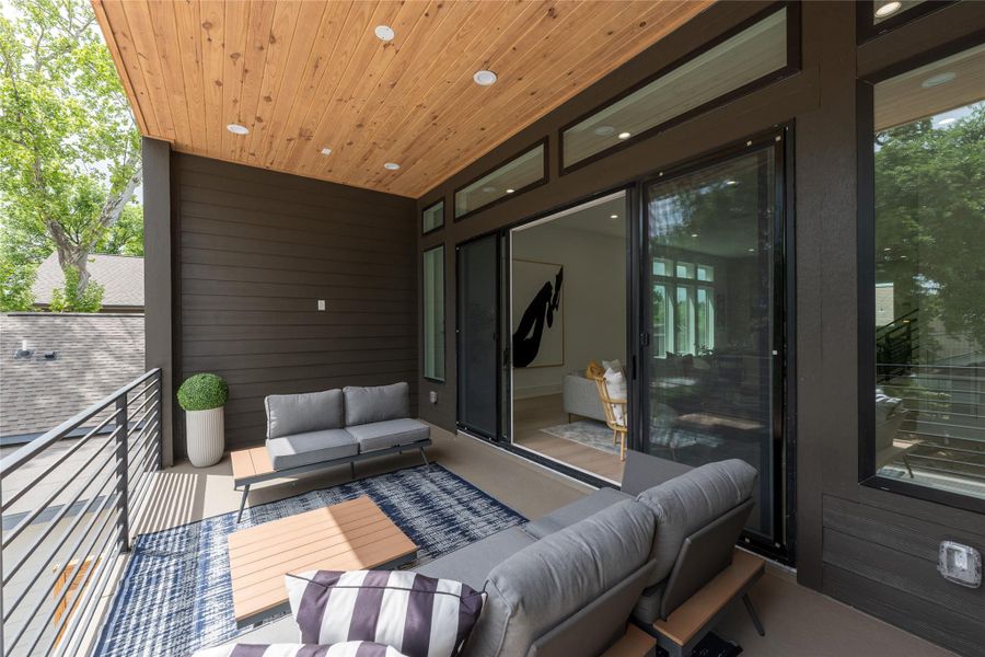 The balcony sits tucked into the canopy, wrapped by horizontal railing, capped by a cedar plank ceiling, and lit by integrated downlights. Truly a room-sized exhale above the street.
