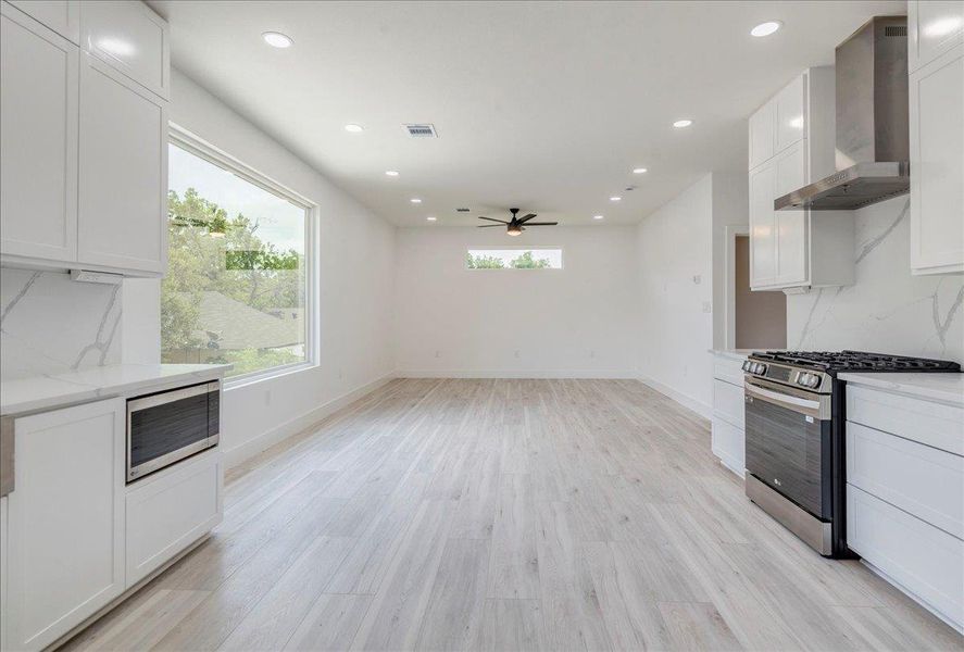Kitchen with range hood, appliances with stainless steel finishes, a ceiling fan, backsplash, and white cabinets Kitchen with range hood, appliances with stainless steel finishes, a ceiling fan, backsplash, and white cabinets