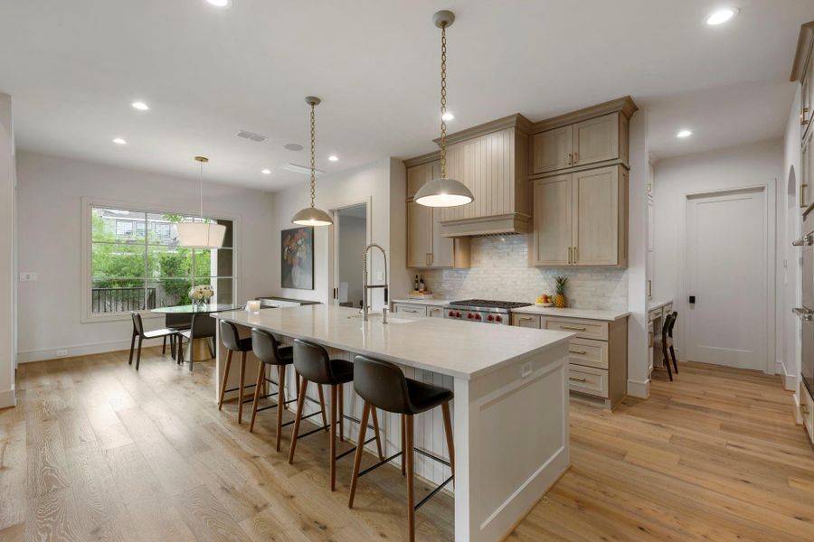 Beautifully appointed kitchen with a generous island for seating, custom cabinetry, a Wolf gas cooktop, and built-in surround sound speakers, along with a bright breakfast area overlooking the backyard—perfect for casual dining and gathering.