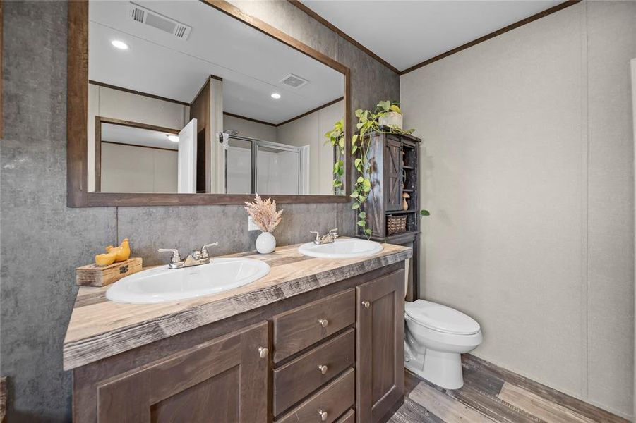 Bathroom featuring light wood-type flooring, double vanity, a shower stall, and ornamental molding Bathroom featuring light wood-type flooring, double vanity, a shower stall, and ornamental molding
