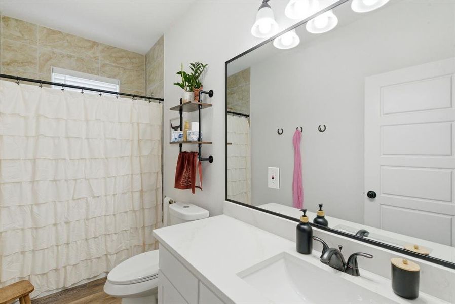 Bathroom with vanity, a shower with shower curtain, and wood finished floors Bathroom with vanity, a shower with shower curtain, and wood finished floors