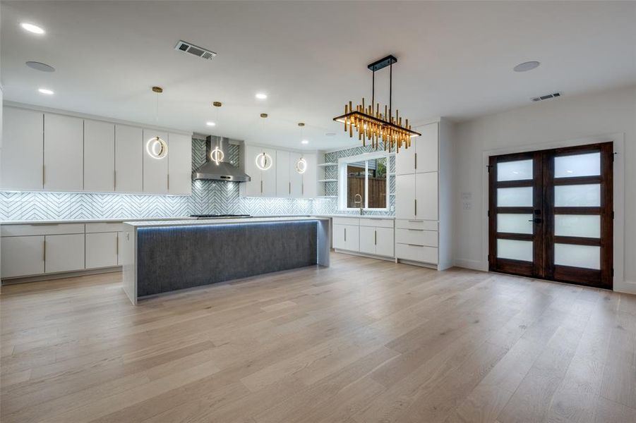 Kitchen featuring a center island, white cabinets, and decorative light fixtures with an open dining area