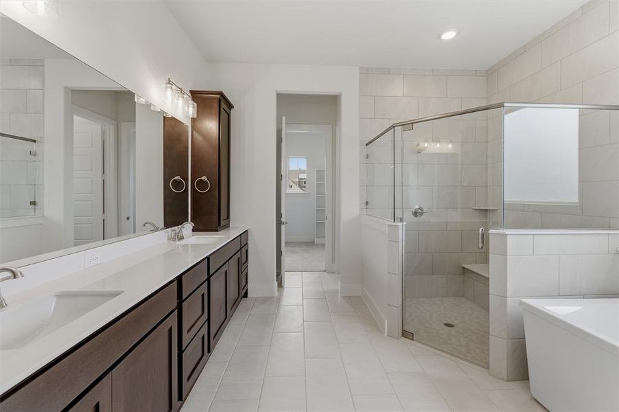 Spacious bathroom featuring a dual vanity with undermount sinks, a dark wood-finish cabinet, and a frameless glass shower enclosure with a built-in bench