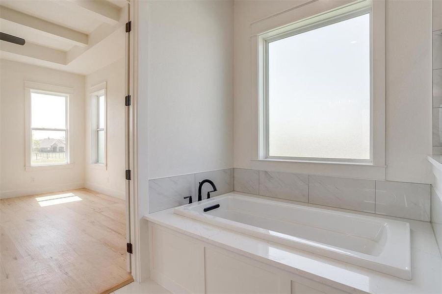 Bathroom featuring a garden tub, wood finished floors, and baseboards
