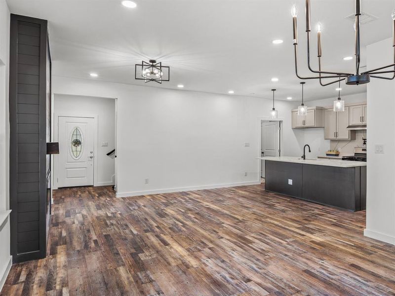 Kitchen with a chandelier, recessed lighting, dark wood-type flooring, pendant lighting, and a center island with sink