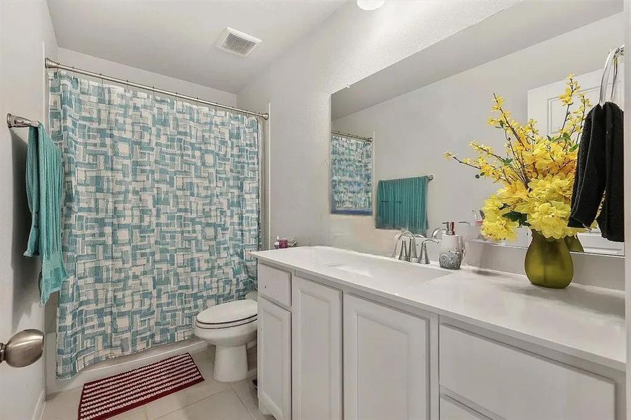 Full bathroom featuring tile patterned floors, vanity, shower / tub combo, and toilet