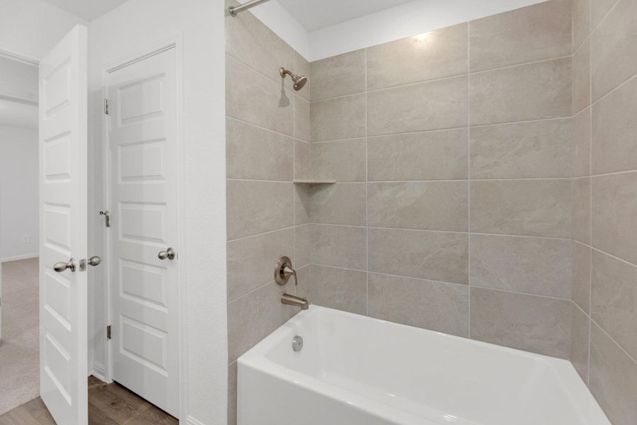 Bathroom featuring washtub / shower combination and wood finished floors Bathroom featuring washtub / shower combination and wood finished floors