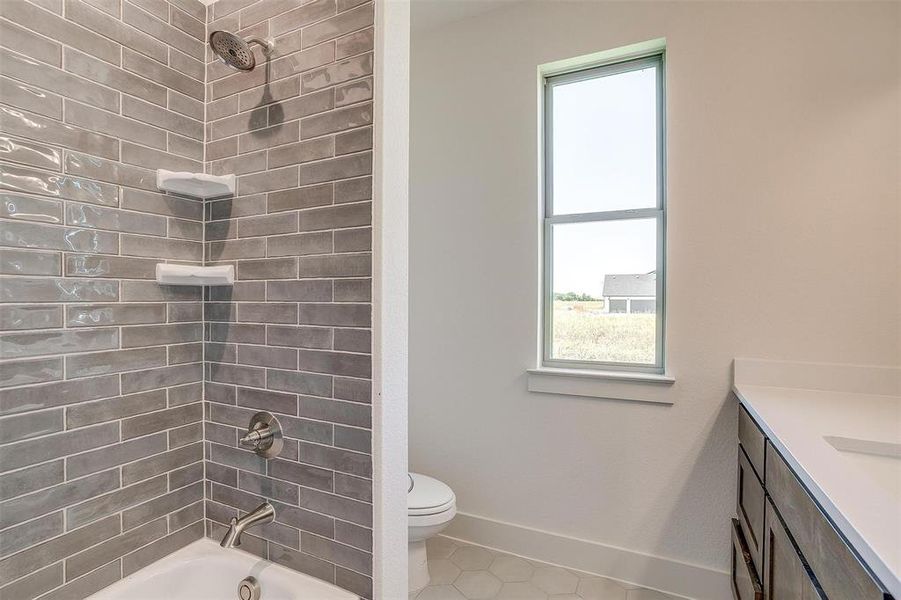 Full bathroom with tile floors, vanity, toilet, and tiled shower / bath combo