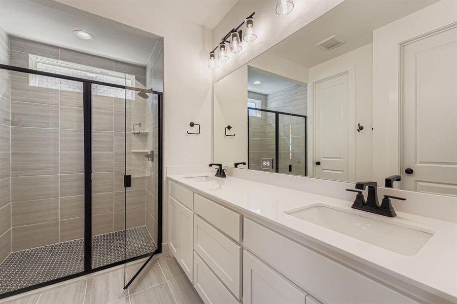 Bathroom featuring a stall shower, double vanity, healthy amount of natural light, light tile patterned flooring, and recessed lighting Bathroom featuring a stall shower, double vanity, healthy amount of natural light, light tile patterned flooring, and recessed lighting
