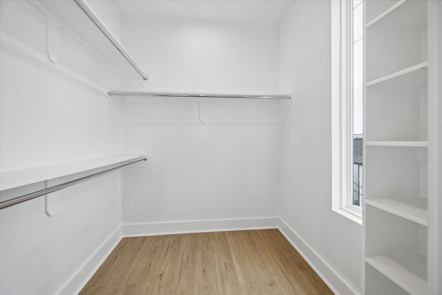Primary closet runs deep, with rods on both walls and built in shelving at the end. Window at the back brings in daylight you rarely get in a closet. Primary closet runs deep, with rods on both walls and built in shelving at the end. Window at the back brings in daylight you rarely get in a closet.