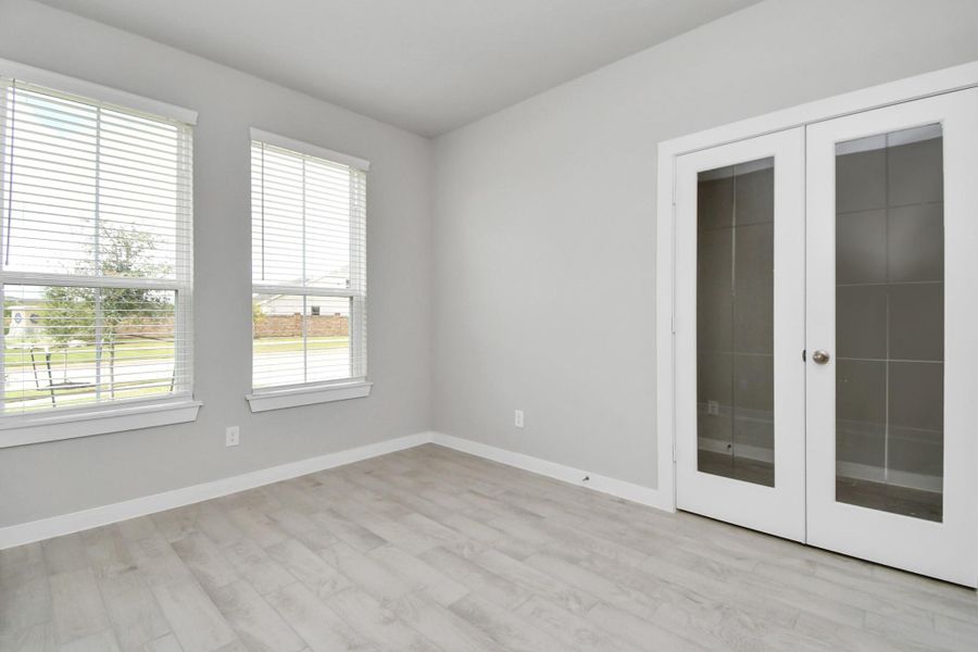 Experience the perfect blend of sophistication and warmth in this home office, boasting elegant wood-look tile flooring and flooded with natural light from expansive windows and French doors. Sample photo of completed home with similar floor plan. Actual colors and selections may vary. Experience the perfect blend of sophistication and warmth in this home office, boasting elegant wood-look tile flooring and flooded with natural light from expansive windows and French doors. Sample photo of completed home with similar floor plan. Actual colors and selections may vary.