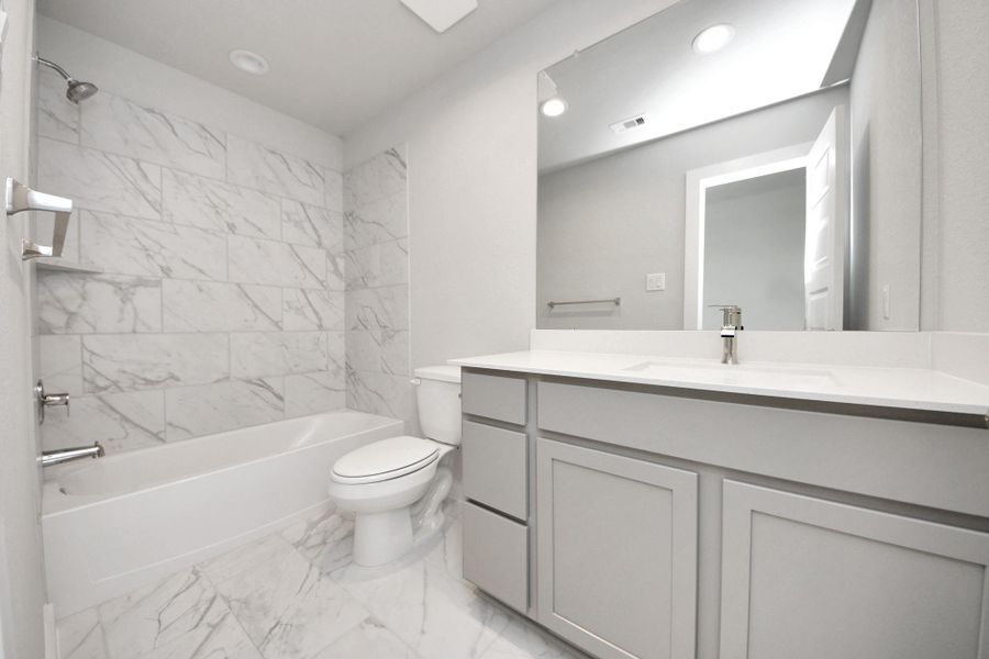 Secondary bath features tile flooring, bath/shower combo with tile surround, light stained wood cabinets, beautiful light countertop. Secondary bath features tile flooring, bath/shower combo with tile surround, light stained wood cabinets, beautiful light countertop.