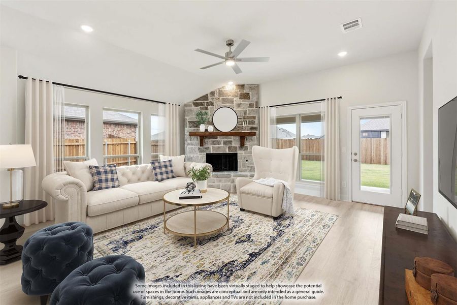 Living room with vaulted ceiling, stone fireplace, ceiling fan, and light hardwood floors