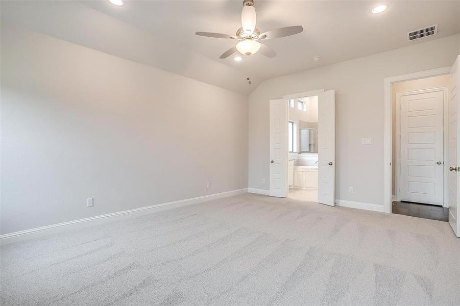 Unfurnished bedroom featuring carpet flooring, ensuite bathroom, and ceiling fan