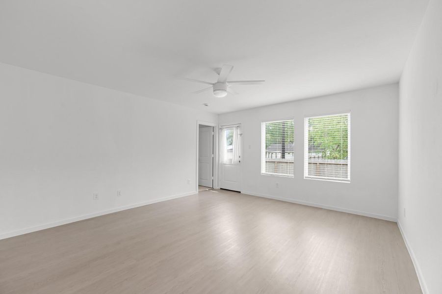 Bright living area features two windows, a ceiling fan, and light-toned flooring, with a rear door providing direct access to the outdoor space. Bright living area features two windows, a ceiling fan, and light-toned flooring, with a rear door providing direct access to the outdoor space.