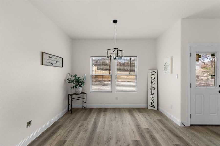 Unfurnished dining area featuring an inviting chandelier and light hardwood / wood-style flooring