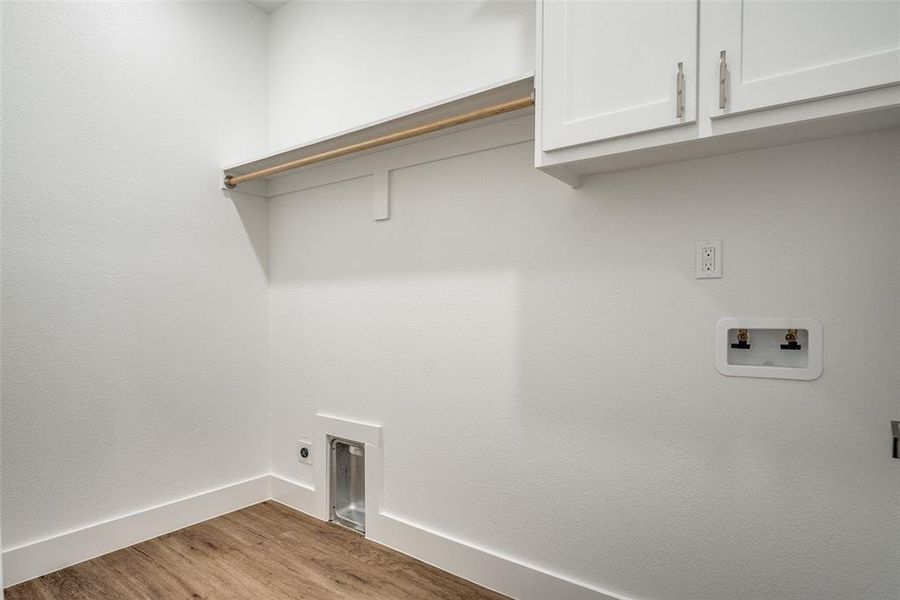 Washroom featuring light wood-style floors, cabinet space, and hookup for a washing machine Washroom featuring light wood-style floors, cabinet space, and hookup for a washing machine