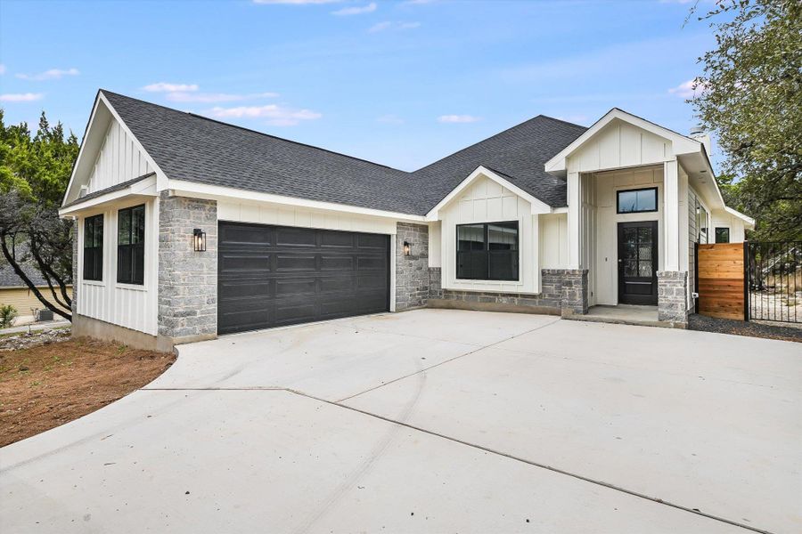 Modern farmhouse style home with board and batten siding, stone siding, roof with shingles, and an attached garage