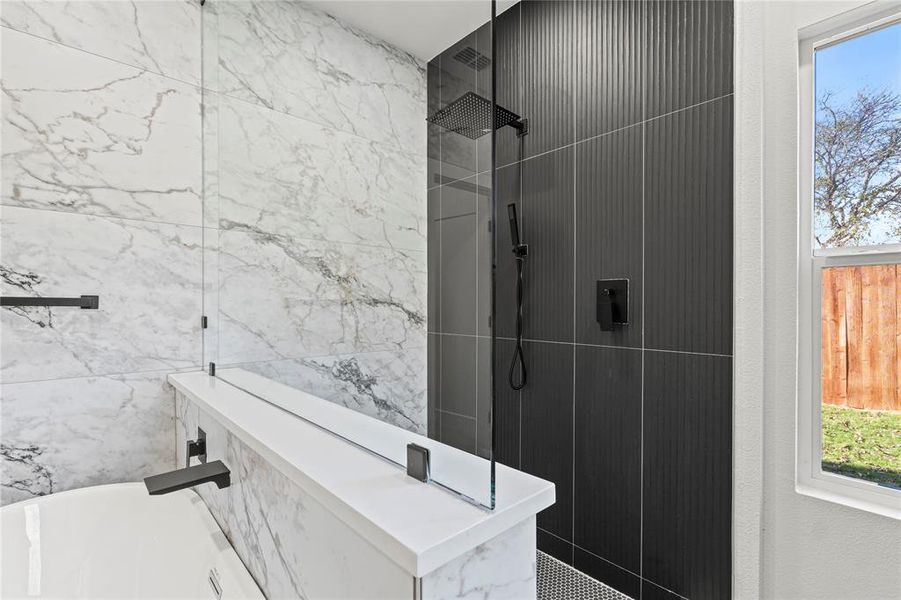 Bathroom with a walk in shower, a freestanding tub, and tile walls