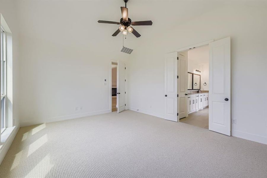 Unfurnished bedroom featuring light colored carpet, ceiling fan, ensuite bathroom, and lofted ceiling Unfurnished bedroom featuring light colored carpet, ceiling fan, ensuite bathroom, and lofted ceiling
