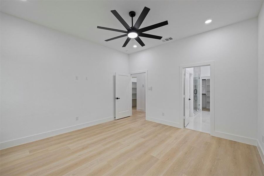 Unfurnished bedroom featuring light wood finished floors, recessed lighting, a ceiling fan, a spacious closet, and ensuite bathroom