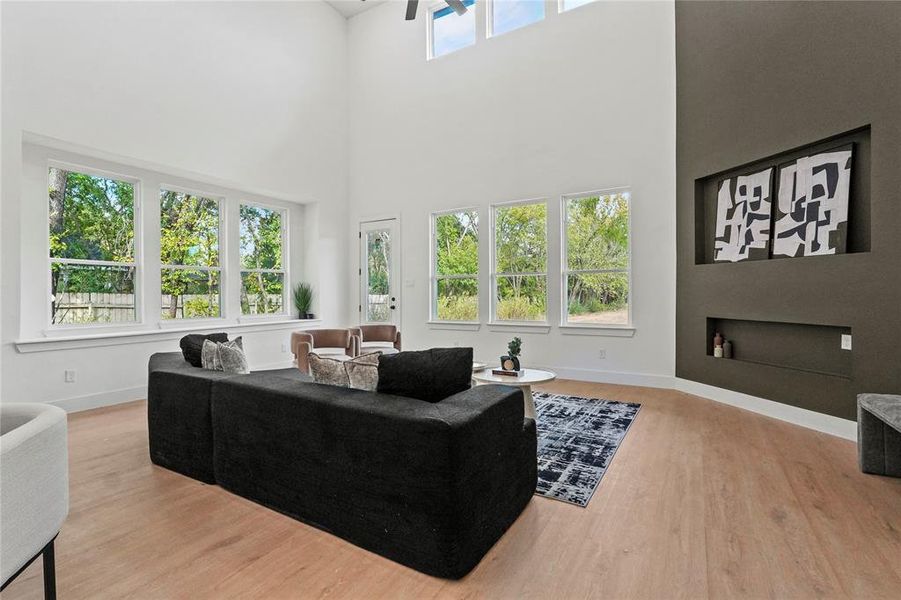 Living area with light wood-style flooring and a towering ceiling Living area with light wood-style flooring and a towering ceiling
