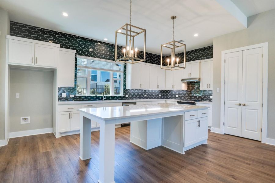 Kitchen featuring white cabinets, a kitchen island, decorative light fixtures, dark hardwood / wood-style flooring, and light stone counters