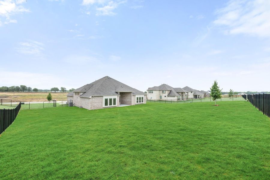 Brick home with large fenced backyard and green lawn in a new subdivision