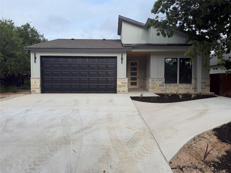 A modern facade with a dark garage door and a clean concrete driveway offers inviting curb appeal.