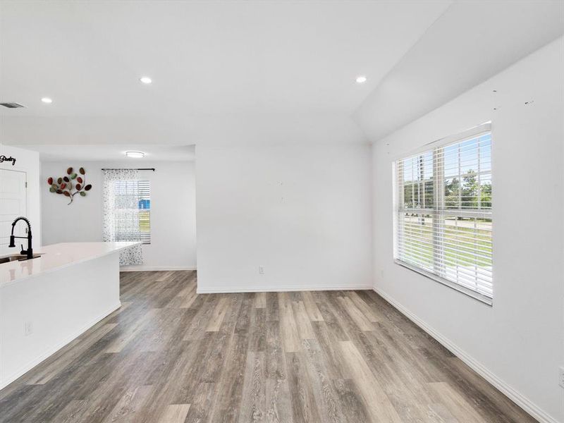Open-concept living space with wood-finish flooring, white walls, and recessed lighting