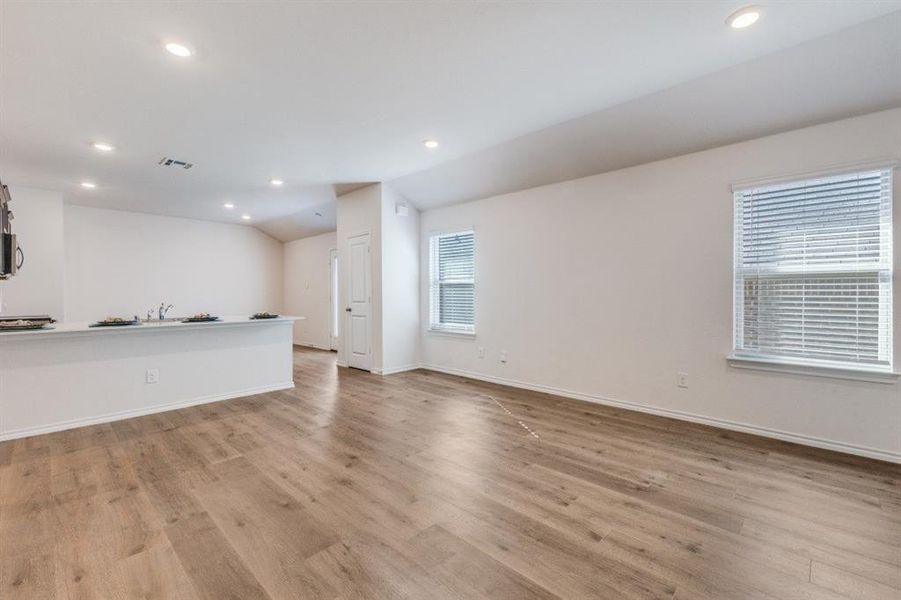 Unfurnished living room featuring lofted ceiling, recessed lighting, and light wood-style floors Unfurnished living room featuring lofted ceiling, recessed lighting, and light wood-style floors