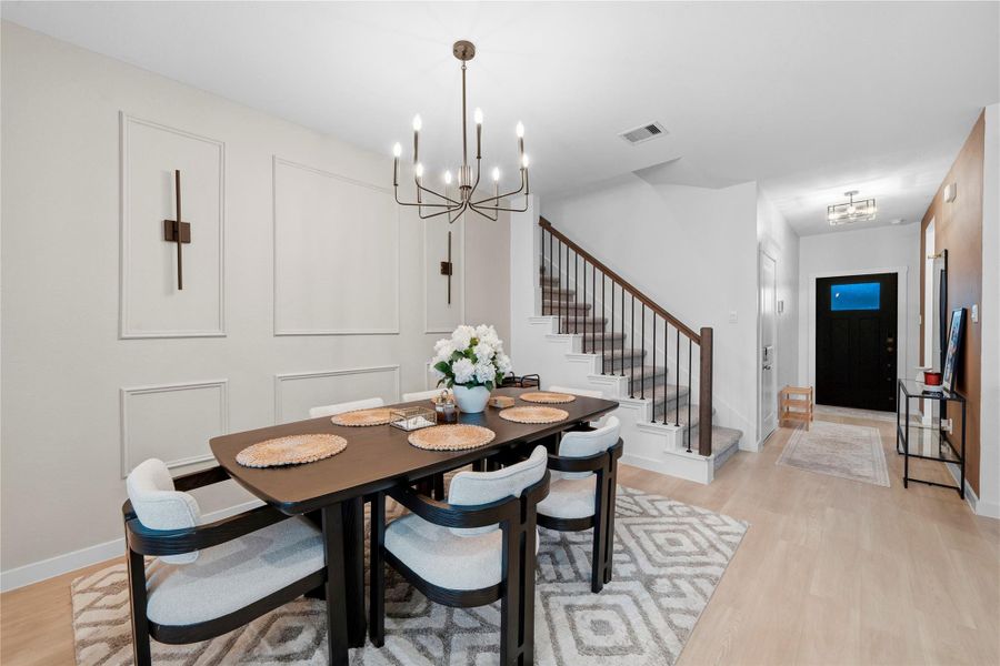 The dining area is elevated by a striking modern chandelier, complemented by elegant wall paneling and a prime location near the entry and staircase. The dining area is elevated by a striking modern chandelier, complemented by elegant wall paneling and a prime location near the entry and staircase.