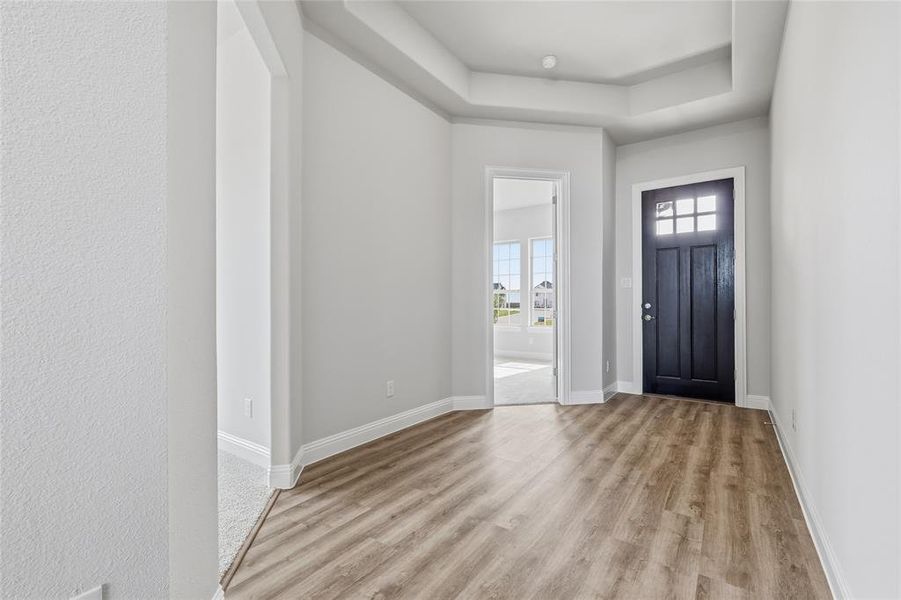 Foyer entrance with a raised ceiling and light wood finished floors Foyer entrance with a raised ceiling and light wood finished floors
