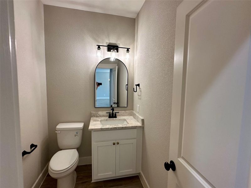 Bathroom featuring vanity, wood finished floors, and a textured wall Bathroom featuring vanity, wood finished floors, and a textured wall